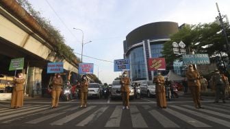 Sejumlah Aparatur Sipil Negara (ASN) membawa poster imbauan saat peresmian simbol peringatan COVID-19 di Simpang Lima Senen, Jakarta, Selasa (1/9/2020). [Suara.com/Angga Budhiyanto]