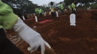 Petugas pemakaman mengali pusara untuk pemakaman penanganan jenazah pasien COVID-19 di TPU Pondok Ranggon, Jakarta, Rabu (2/9/2020). [Suara.com/Angga Budhiyanto]