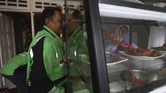 Petugas melayani pengemudi ojek onlne yang akan menikmati hidangan makan gratis di Warung Makan Rakyat, Beji, Depok, Jawa Barat, Kamis (3/9/2020). [Suara.com/Angga Budhiyanto]