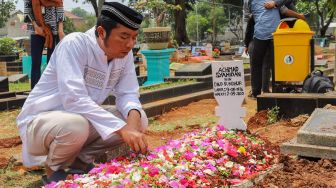 Komedian Udin Penyok berdoa diatas pusara Idan Separo di TPU Poncol, Bekasi, Jawa Barat, Kamis (3/9). [Suara.com/Alfian Winanto]