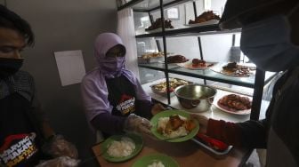 Petugas melayani warga yang akan menikmati hidangan makan gratis di Warung Makan Rakyat, Beji, Depok, Jawa Barat, Kamis (3/9/2020). [Suara.com/Angga Budhiyanto]