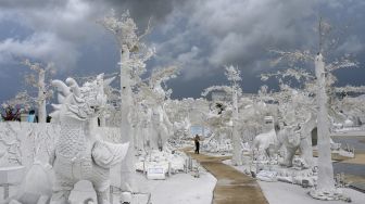 Seorang karyawan berjalan di antara patung-patung mitos yang terbuat dari pasir putih yang menyerupai es di taman "Frost Magical Ice of Siam" di luar Pattaya, Thailand (2/9/2020). [Mladen ANTONOV / AFP]