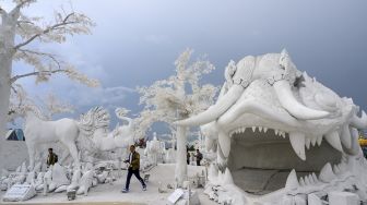 Pengunjung berfoto di depan patung yang terbuat dari pasir putih yang menyerupai es di taman "Frost Magical Ice of Siam" di luar Pattaya, Thailand (2/9/2020). [Mladen ANTONOV / AFP]