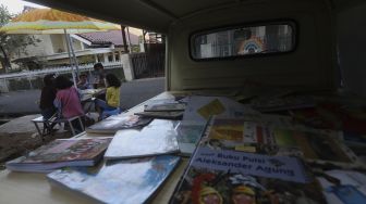 Sejumlah anak membaca buku koleksi dari Bemo Baca milik Sutino (60) bertepatan dengan Hari Aksara Internasional (HAI) di Jakarta, Selasa (8/9/2020). [Suara.com/Angga Budhiyanto]