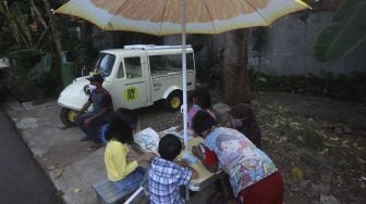 Sejumlah anak membaca buku koleksi dari Bemo Baca milik Sutino (60) bertepatan dengan Hari Aksara Internasional (HAI) di Jakarta, Selasa (8/9/2020). [Suara.com/Angga Budhiyanto]