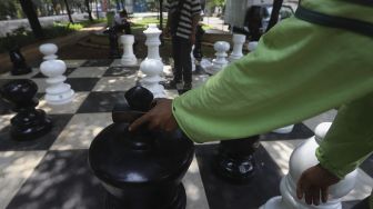 Petugas Sudin Pertamanan dan Kehutanan Jakarta Pusat bersama warga bermain catur raksasa di sela-sela waktu istirahatnya di Taman Danau Singkarak, Bendungan Hilir, Jakarta, Rabu (9/9/2020). [Suara.com/Angga Budhiyanto]