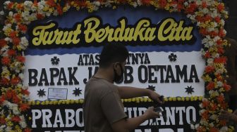 Petugas merapikan karangan bunga tanda berduka cita atas meninggalnya almarhum Pendiri Kompas Gramedia/ Pemimpin Umum Harian Kompas Jakob Oetama di rumah duka di jalan Sriwijaya, Jakarta, Rabu (9/9/2020). [Suara.com/Angga Budhiyanto]