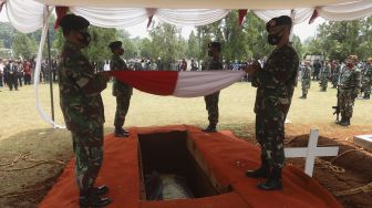 Peronel TNI membentangkan bendera Merah Putih di atas peti jenazah Pendiri Kompas Gramedia/Pemimpin Umum Harian Kompas Jakob Oetama di Taman Makam Pahlawan (TMP) Kalibata, Jakarta, Kamis (10/9/2020). [Suara.com/Angga Budhiyanto]