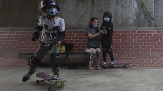 Orang tua membantu memasangkan pelindung tubuh kepada anaknya sebelum berlatih skateboard di Crooz School of Skate di kawasan Duren Tiga, Jakarta, Sabtu (12/9/2020). [Suara.com/Angga Budhiyanto]