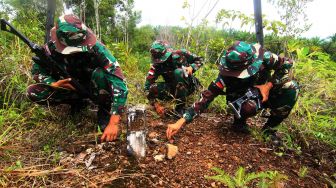 Tiga anggota Satgas Pamtas RI-Malaysia Yonif 133/Yudha Sakti membersihkan rumput di sekitar patok batas saat patroli di perbatasan Badau, Kabupaten Kapuas Hulu, Kalimantan Barat, Jumat (11/9/2020).  [ANTARA FOTO/Jessica Helena Wuysang]
