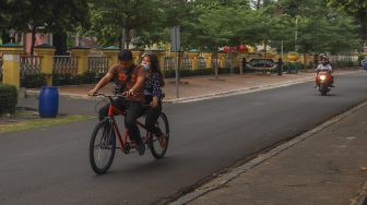 Warga bersepeda di Taman Mini Indonesia Indah, Jakarta Timur, Minggu (13/9). [Suara.com/Alfian Winanto]