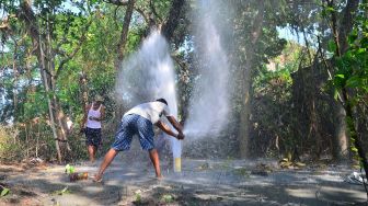 Warga berusaha menutup semburan air dari sumur bor di Desa Manggarmas, Godong, Grobogan, Jawa Tengah, Minggu (13/9/2020). [ANTARA FOTO/Yusuf Nugroho]

