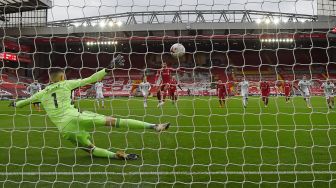 Penjaga gawang Leeds United Illan Meslier (kiri) gagal menyelamatkan gawangnya saat gelandang Liverpool Mohamed Salah menembak dari titik penalti untuk mencetak gol pembuka timnya  selama pertandingan sepak bola Liga Premier Inggris antara Liverpool melawan Leeds United di Anfield, Liverpool, Inggris, Mingggu (13/9) dini hari WIB. [Paul ELLIS / POOL / AFP]