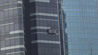 Pekerja membersihkan kaca di salah satu gedung perkantoran di kawasan Kuningan, Jakarta, Senin (14/9/2020). [Suara.com/Angga Budhiyanto]