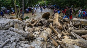 Sejumlah warga berada di depan tumpukan kayu yang menimbun jalan dan rumah akibat banjir bandang di Desa Rogo, Kecamatan Dolo Selatan, Kabupaten Sigi, Sulawesi Tengah, Selasa (15/9/2020). [ANTARA FOTO/Basri Marzuki]