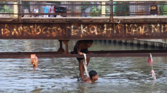 Anak - anak bermain air dibawah jembatan saat berenang di saluran Kalimalang, Kalimalang, Jakarta Timur, Selasa (15/9). [Suara.com/Alfian Winanto]