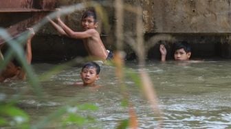 Anak - anak berenang di saluran Kalimalang, Kalimalang, Jakarta Timur, Selasa (15/9). [Suara.com/Alfian Winanto]