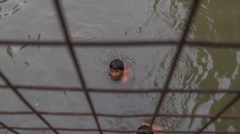 Anak - anak berenang dibawah jembatan di saluran Kalimalang, Kalimalang, Jakarta Timur, Selasa (15/9). [Suara.com/Alfian Winanto]