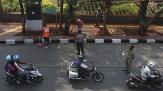Dua warga yang terjaring operasi yustisi protokol kesehatan pencegahan Covid-19 karena tidak mengenakan masker menjalani sanksi sosial di jalan Taman Margasatwa, Jati padang, Jakarta Selatan, Selasa (15/9/2020). [Suara.com/Angga Budhiyanto]