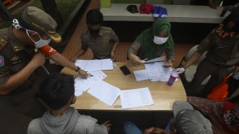 Petugas mendata warga yang tidak mengenakan masker saat operasi yustisi protokol kesehatan pencegahan Covid-19 di jalan Taman Margasatwa, Jati padang, Jakarta Selatan, Selasa (15/9/2020). [Suara.com/Angga Budhiyanto]