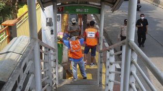 Dua warga yang terjaring operasi yustisi protokol kesehatan pencegahan Covid-19 karena tidak mengenakan masker menjalani sanksi sosial di jalan Taman Margasatwa, Jati padang, Jakarta Selatan, Selasa (15/9/2020). [Suara.com/Angga Budhiyanto]