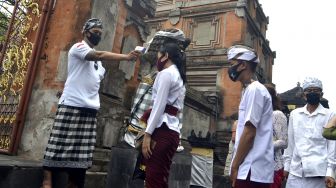 Pecalang atau petugas pengamanan adat Bali memeriksa suhu tubuh umat Hindu yang akan bersembahyang saat Hari Raya Galungan di Pura Jagatnatha, Denpasar, Bali, Rabu (16/9/2020). [ANTARA FOTO/Fikri Yusuf]