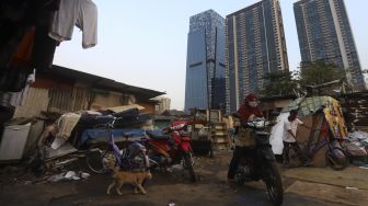 Warga beraktivitas dengan latar belakang deretan gedung perkantoran di permukiman padat penduduk di kawasan Menteng Pulo, Jakarta, Rabu (16/9/2020). [Suara.com/Angga Budhiyanto]