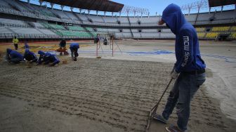 Pekerja membuat lubang untuk pemasangan bibit rumput di lapangan Stadion Gelora Bung Tomo (GBT), Surabaya, Jawa Timur, Jumat (18/9/2020).  [ANTARA FOTO/Moch Asim]
