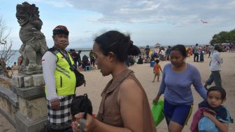 Pecalang atau petugas keamanan desa adat di Bali menegur wisatawan yang melepas masker saat liburan Hari Raya Galungan di Pantai Sanur, Denpasar, Bali, Kamis (17/9/2020).  [ANTARA FOTO/Nyoman Hendra Wibowo]