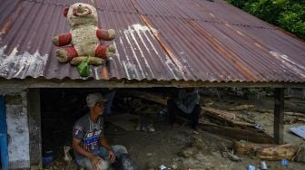 Warga berada di rumahnya yang tertimbun lumpur akibat banjir bandang di Desa Rogo, Kecamatan Dolo Selatan, Kabupaten Sigi, Sulawesi Tengah, Selasa (15/9/2020). Banjir bandang yang terjadi pada Senin (14/9/2020) malam karena hujan lebat itu mengakibatkan sedikitnya 15 rumah warga rusak berat dan puluhan lainnya rusak ringan dan digenangi lumpur. Sebanyak 59 Kepala Keluarga atau atau 224 jiwa terpaksa mengungsi ke tempat aman. [ANTARA FOTO/Basri Marzuki]