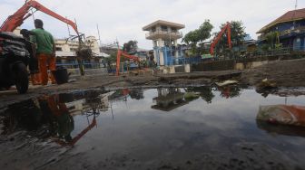 Petugas UPK Badan Air Dinas Lingkungan Hidup Provinsi DKI Jakarta dibantu alat berat mengangkat sampah kayu yang menumpuk di pintu air Manggarai, Jakarta, Selasa (22/9/2020). [Suara.com/Angga Budhiyanto]