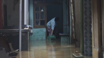 Warga membersihkan rumahnya yang terendam banjir di kawasan Kebon Pala, Kampung Melayu, Jakarta, Selasa (22/9/2020). [Suara.com/Angga Budhiyanto]