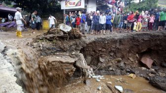 Warga melihat jalanan yang rusak pasca banjir bandang di Kampung Cibuntu, Desa Pasawahan, Kecamatan Cicurug, Sukabumi, Jawa Barat, Selasa (22/9/2020). [ANTARA FOTO/Yulius Satria Wijaya]

