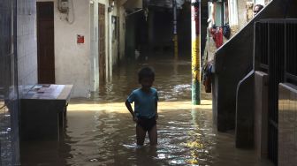 Seorang anak melintasi banjir yang merendam kawasan Kebon Pala, Kampung Melayu, Jakarta, Selasa (22/9/2020). [Suara.com/Angga Budhiyanto]