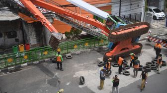 Petugas mengevakuasi ekskavator yang terguling menimpa tangga jembatan penyeberangan orang (JPO) di Kampung Melayu, Jakarta, Selasa (22/9/2020).  [ANTARA FOTO/Akbar Nugroho Gumay]
