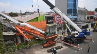 Petugas mengevakuasi ekskavator yang terguling menimpa tangga jembatan penyeberangan orang (JPO) di Kampung Melayu, Jakarta, Selasa (22/9/2020).  [ANTARA FOTO/Akbar Nugroho Gumay]
