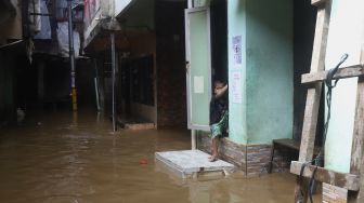 Seorang anak berada di rumahnya yang terendam banjir di kawasan Kebon Pala, Kampung Melayu, Jakarta, Selasa (22/9/2020). [Suara.com/Angga Budhiyanto]