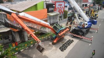 Petugas mengevakuasi ekskavator yang terguling menimpa tangga jembatan penyeberangan orang (JPO) di Kampung Melayu, Jakarta, Selasa (22/9/2020).  [ANTARA FOTO/Akbar Nugroho Gumay]
