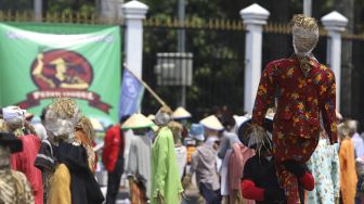 Seorang massa yang tergabung dalam Komite Nasional Pembaruan Agraria (KNPA) membawa boneka jerami atau orang-orangan sawah saat menggelar aksi Hari Tani Nasional  di depan gedung DPR RI, Jakarta, Kamis (24/9/2020). [Suara.com/Angga Budhiyanto]