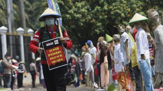 Seorang massa yang tergabung dalam Komite Nasional Pembaruan Agraria (KNPA) membawa poster protes saat menggelar aksi Hari Tani Nasional  di depan gedung DPR RI, Jakarta, Kamis (24/9/2020). [Suara.com/Angga Budhiyanto]