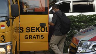 Keluarga pasien tanpa gejala COVID-19 membantu menaikkan barang bawaan pasien ke dalam bus sekolah di Puskesmas Kecamatan Makassar, Jakarta, Kamis (24/9/2020). [Suara.com/Angga Budhiyanto]