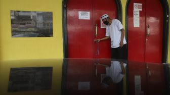 Pengurus masjid menutup pintu masuk Masjid Lautze, Sawah Besar, Jakarta, Senin (28/9/2020). [Suara.com/Angga Budhiyanto]