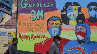 Warga melintas didepan mural Covid-19 yang berisi himbauan memakai masker di Terowongan Stasiun Cawang, Tebet, Jakarta Selatan, Senin (28/9). [Suara.com/Alfian Winanto]