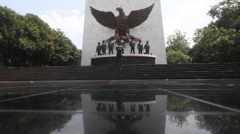 Pengunjung berfoto di depan Monumen Pancasila Sakti di Lubang Buaya, Jakarta, Kamis (1/10/2020). [Suara.com/Angga Budhiyanto]