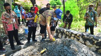 Kepala Seksi Energi Dinas ESDM wilayah Kendeng Selatan Sinung Sugeng Arianto (tengah) mengecek kadar gas di lokasi semburan air dan gas di Desa Manggarmas, Godong, Grobogan, Jawa Tengah, Jumat (2/10/2020). [ANTARA FOTO/Yusuf Nugroho]
