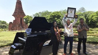 Direktur Perfilman, Musik dan Media Baru Kemendikbud Ahmad Mahendra (kanan) bersama Senior Manager MURI Sri Widayati (kiri) menyaksikan Presiden Direktur PT Saniharto Enggalhardjo Harsono Enggalhardjo (tengah) mengangkat piagam MURI untuk 'grand piano pertama buatan Indonesia' saat digelar rangkaian konser Raspodia Nusantara dan Kejayaan Nusantara di Candi Gapura Bajang Ratu, Trowulan, Mojokerto, Jawa Timur, Sabtu (3/10/2020). [ANTARA FOTO/Zabur Karuru]