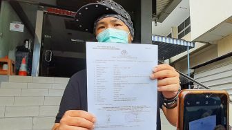 Youtuber dan Tatoo Artist Hendric Shinigami menunjukkan surat laporan kepolisian terkait pencemaran nama baik di Polda Metro Jaya, Jakarta Selatan, Sabtu (3/10). [Suara.com/Alfian Winanto]