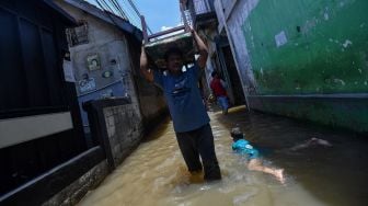 Seorang warga membawa kursi di atas kepalanya saat banjir melanda kawasan permukiman di Petogogan, Kebayoran Baru, Jakarta Selatan, Senin (5/10/2020). Banjir tersebut terjadi akibat meluapnya Kali Krukut. [ANTARA FOTO/Sigid Kurniawan]