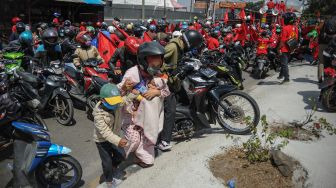 Pengendara yang terjebak kemacetan di jalan nasional Bandung-Garut-Tasikmalaya saat aksi buruh di Rancaekek mengangkat motornya untuk pindah jalur di Kabupaten Bandung, Jawa Barat, Selasa (6/10/2020). [ANTARA FOTO/Raisan Al Farisi]