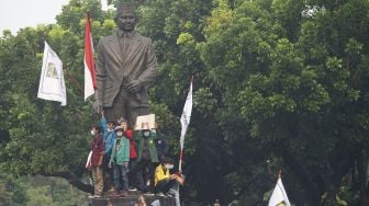 Pengunjuk rasa yang menolak pengesahan Undang-Undang Cipta Kerja menaiki patung pahlawan MH. Thamrin di Jalan Medan Merdeka Selatan, Jakarta, Kamis (8/10/2020). [ANTARA FOTO/Aditya Pradana Putra]